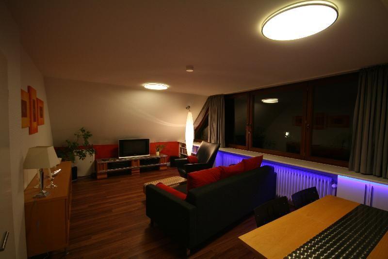 Wohnzimmer mit verdeckter LED RGB Lichtleiste im Einbauschrank für eine indirekte Beleuchtung. Die Farben können Sie mittels Fernbedienung selber bestimmen