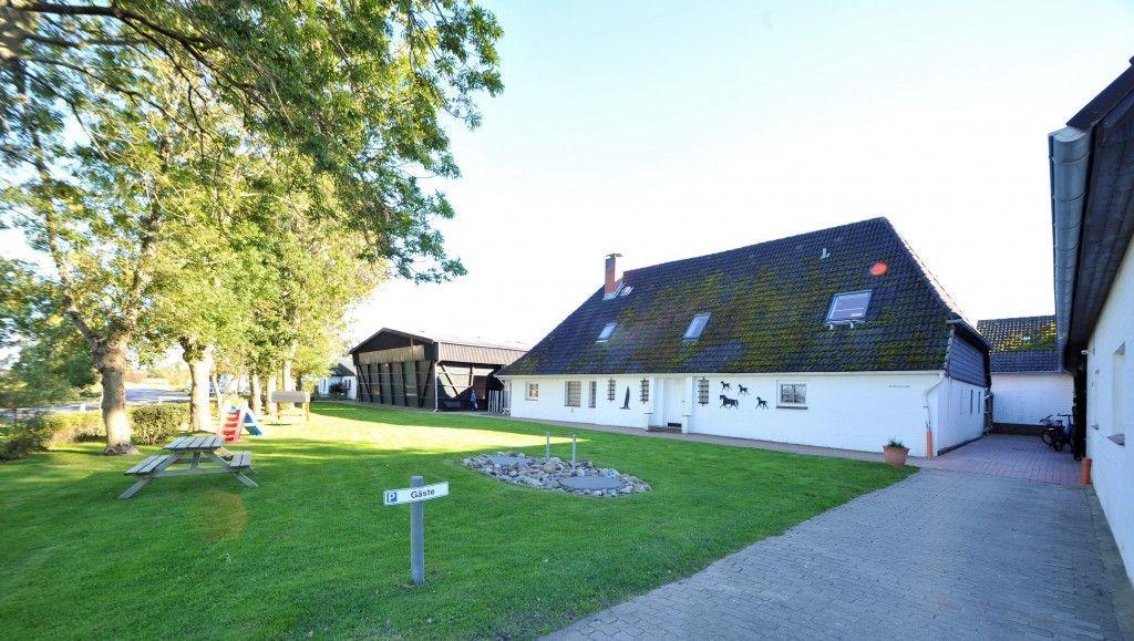 Wohnhaus mit Garten, Picknicktisch und Spielplatz. Weißes Gebäude mit dunklem Dach.