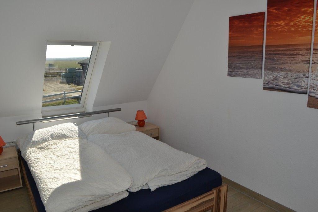 Schlafzimmer mit Dachfenster, Bett und Wandbildern.