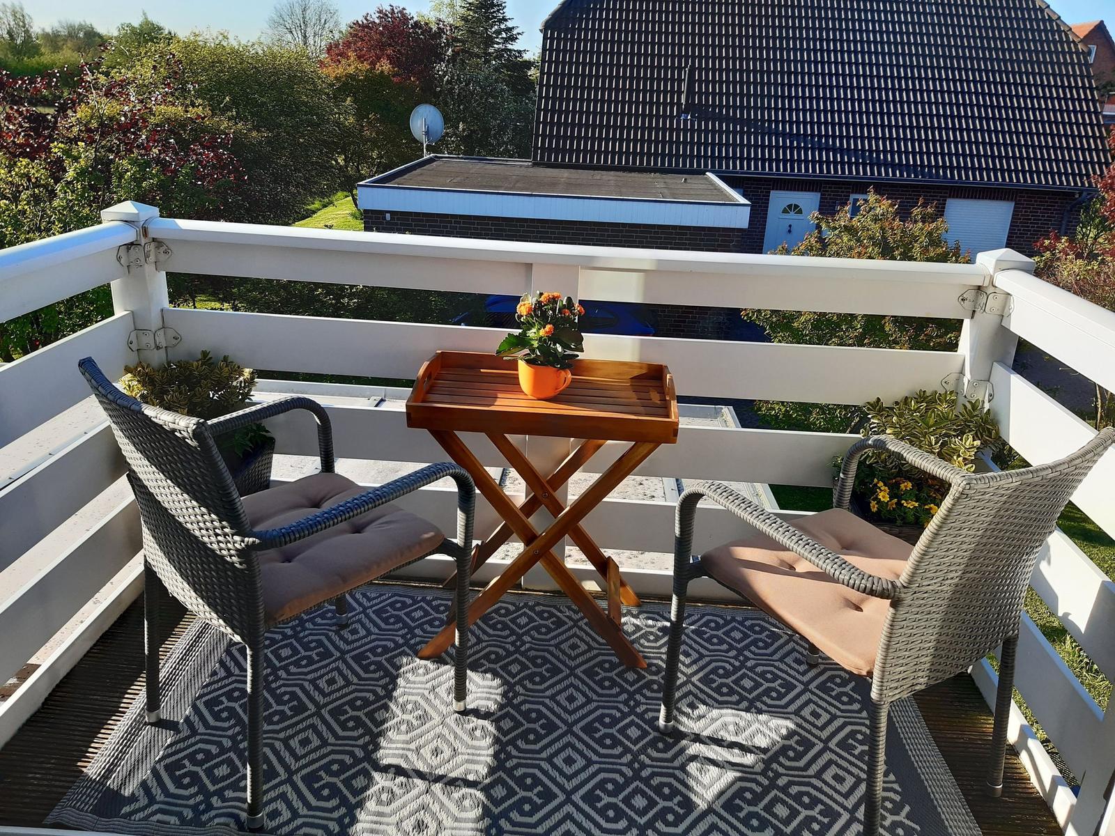 Terrasse mit Tisch und zwei Stühlen, Bezug auf Garten und Haus.