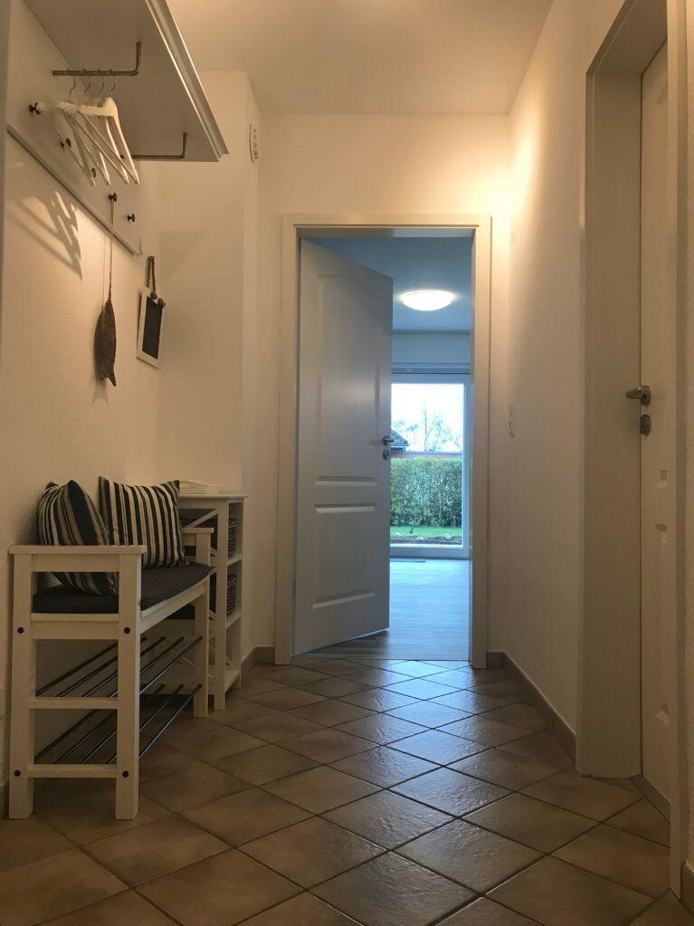 Flur mit Sitzbank, Kleiderhaken und Tür zum Balkon.