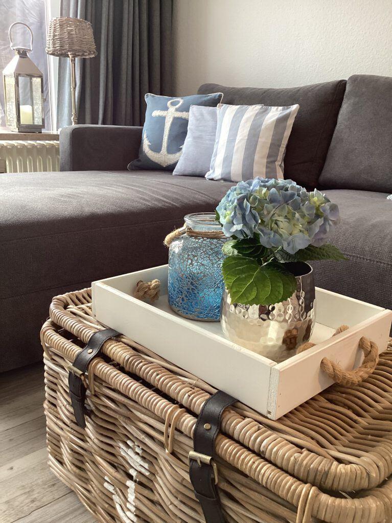 Ein grauer Sofa mit Kissen und ein Korb mit Deko auf einem Couchtisch.