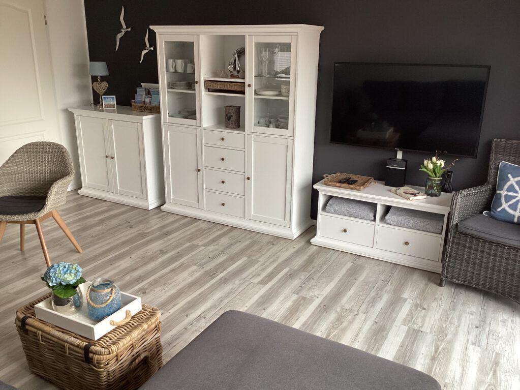 Wohnzimmer mit weißem Sideboard, Fernseher und Sitzgelegenheiten.