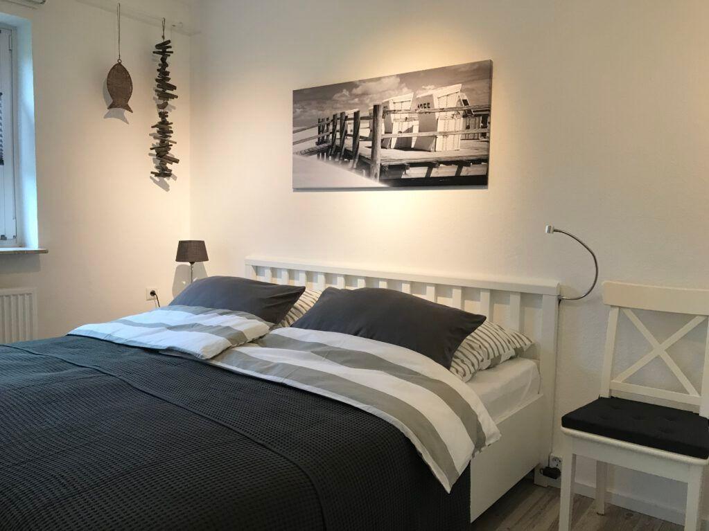 Schlafzimmer mit Bett, Wandbild und Stuhl.