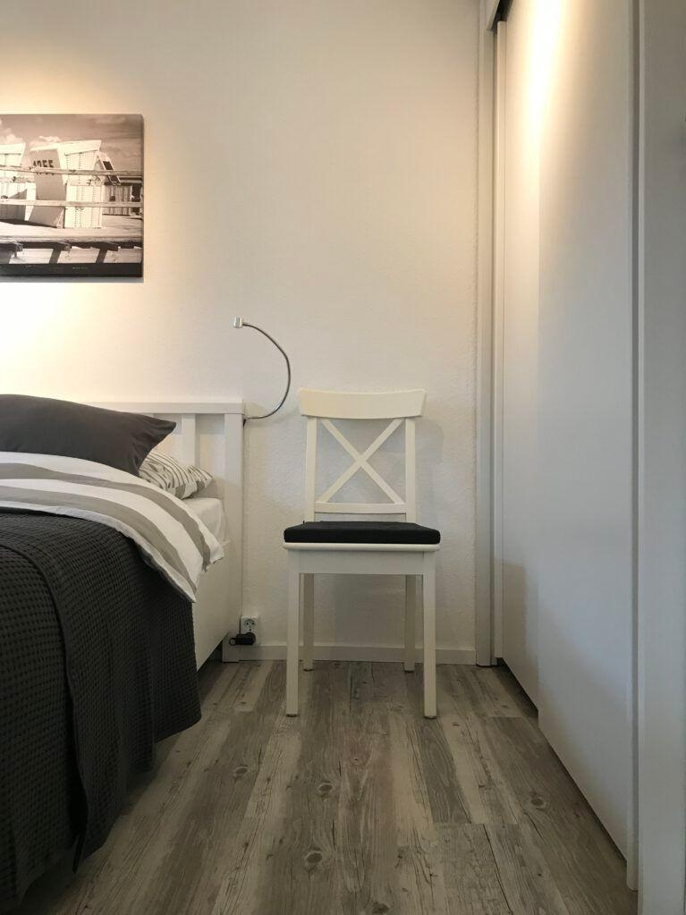 Schlafzimmer mit Bett, Stuhl und Wandbild