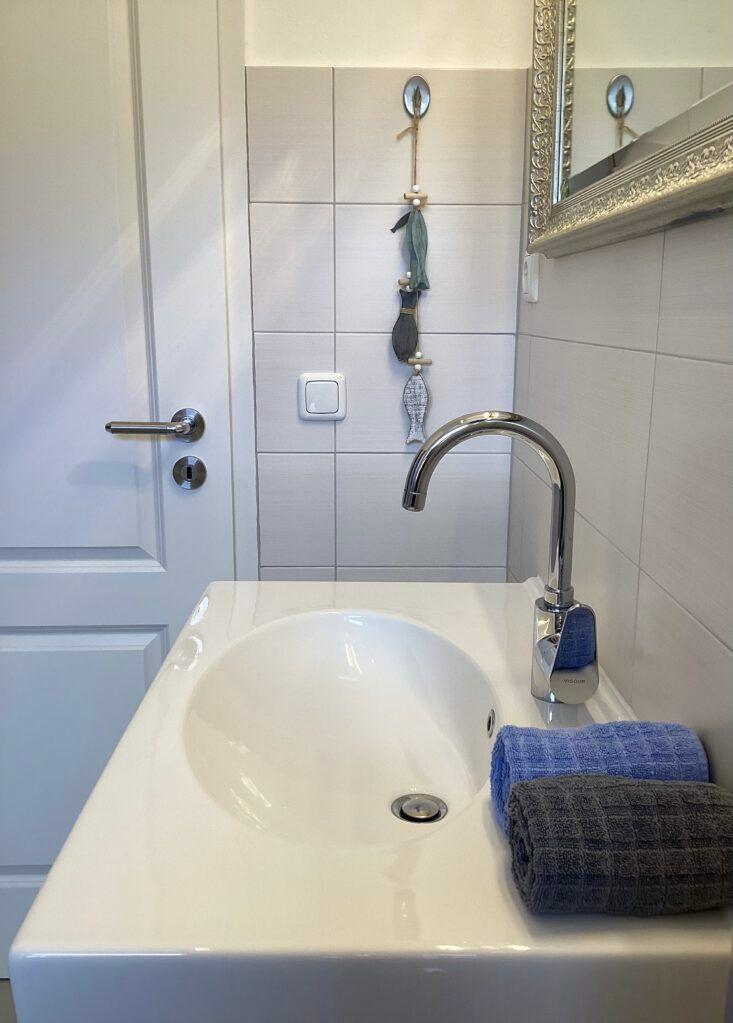 Waschbecken mit Spiegel, Wasserhahn und Handtüchern