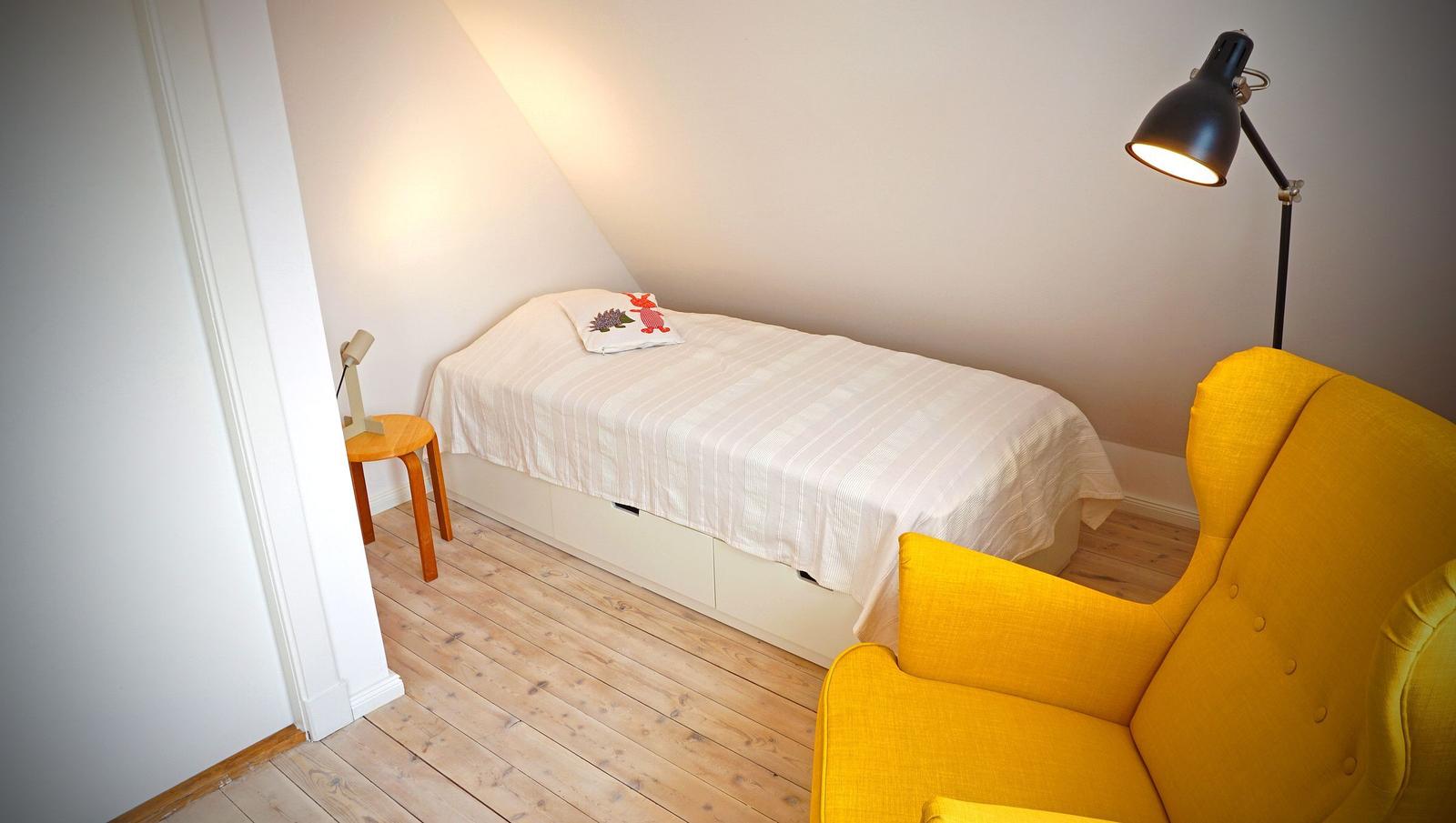 Ein Schlafzimmer mit einem Bett, einem gelben Sessel und einer Stehlampe.