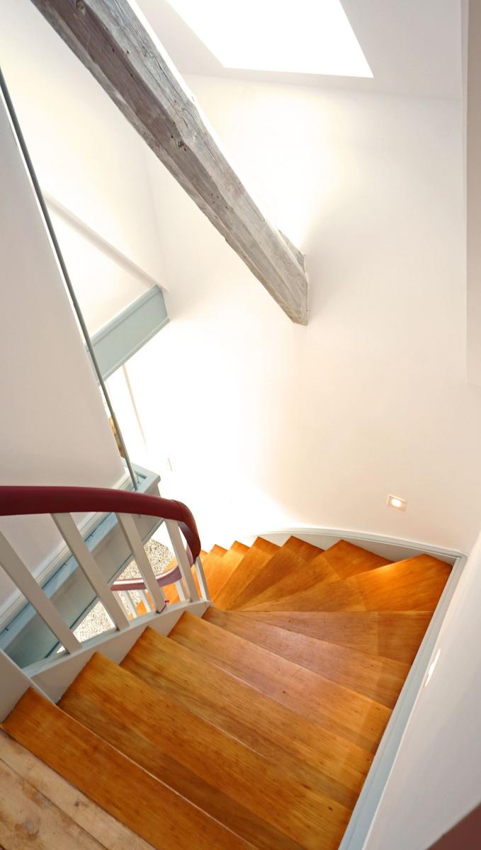 Holzgetreppe mit rotem Handlauf und großer Balken an der Decke.