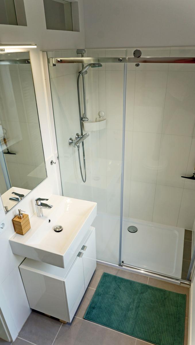 Badezimmer mit Dusche, Waschbecken und Spiegel