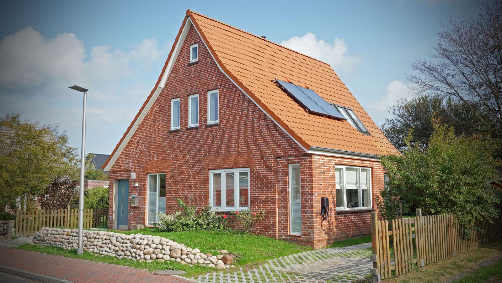 Ein rotes Backsteingebäude mit Dachfenstern und Solaranlage.