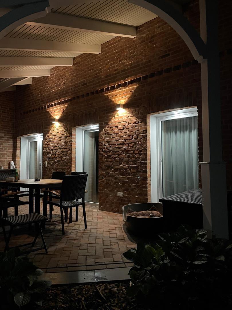 Außenbereich mit Tisch, Stühlen und Beleuchtung an Backsteinwand