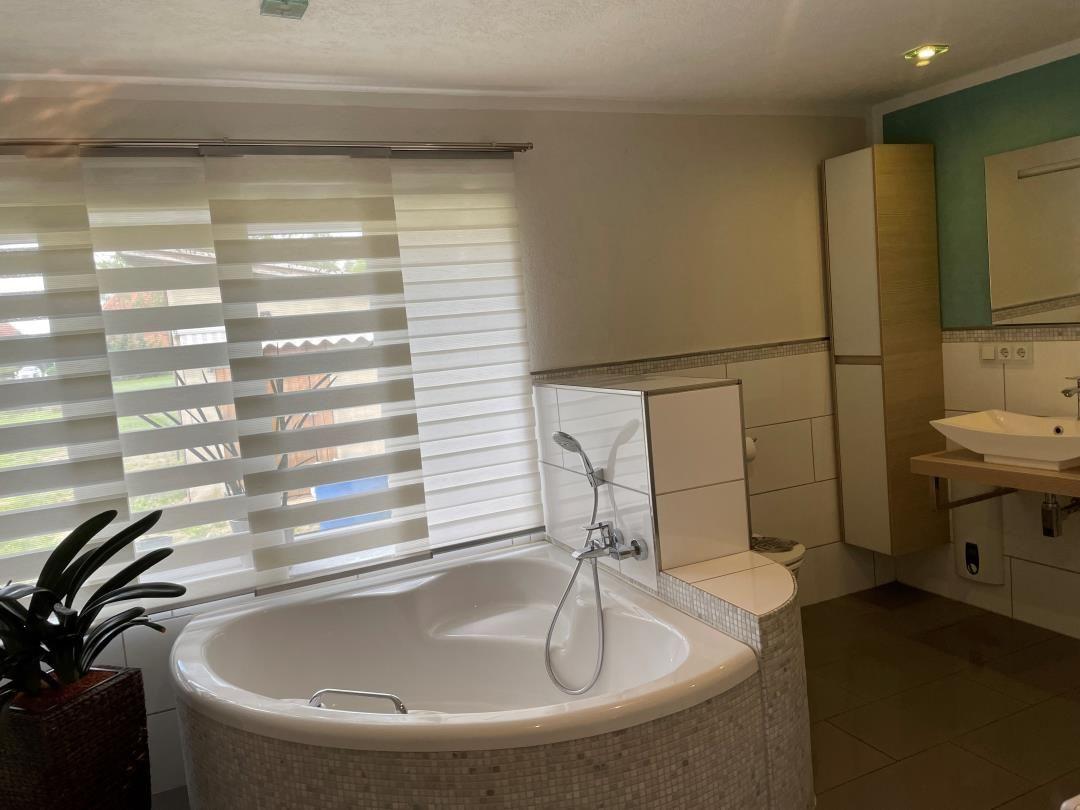 Bad mit Whirlpool, Waschbecken und Fenster mit Jalousie