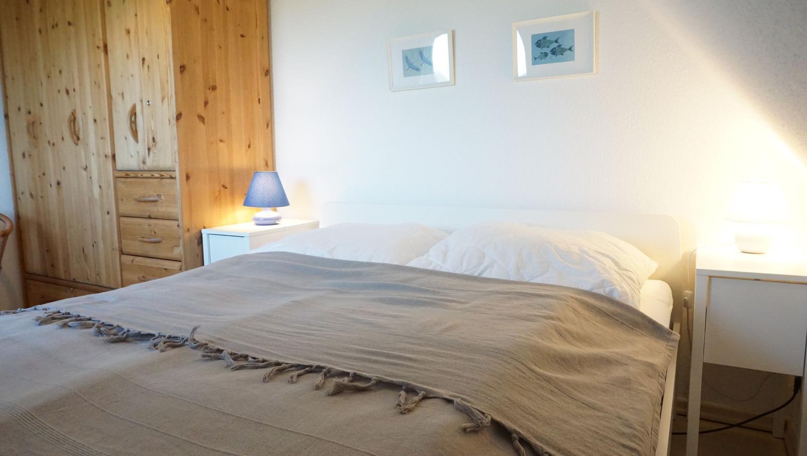 Schlafzimmer mit Bett, Nachttischen und Holzschrank an der Wand.