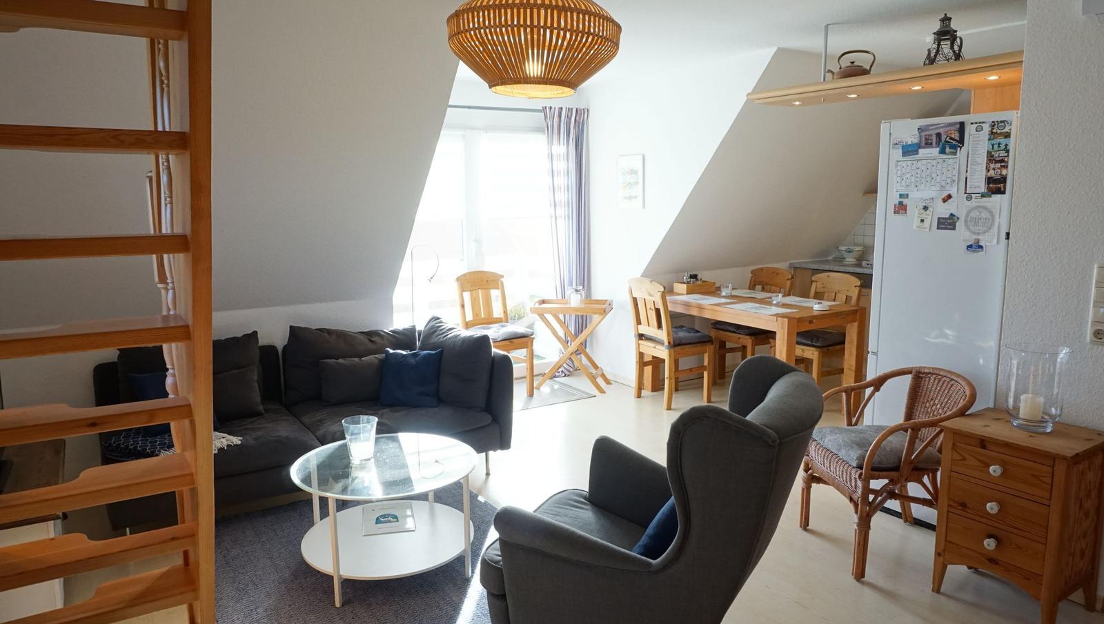 Wohn- und Essbereich mit Sofa, Sessel, Esstisch und Küchenzeile unter Dachschrägen.