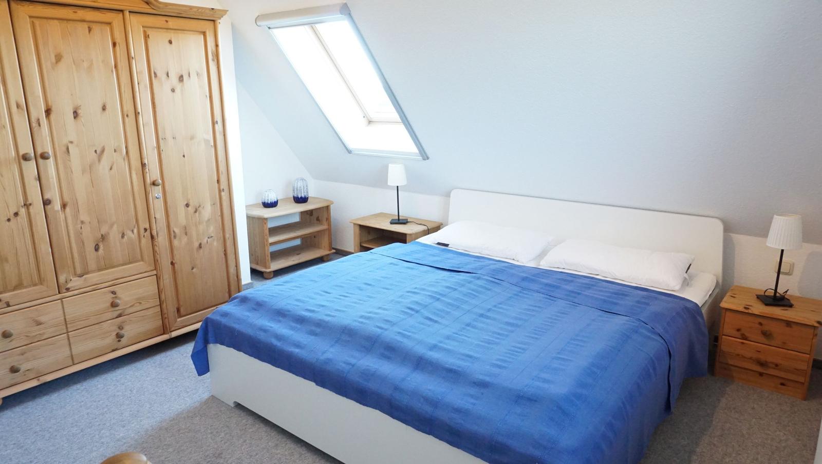 Schlafzimmer mit Dachschrägen, Bett, Kleiderschrank und Nachttisch.