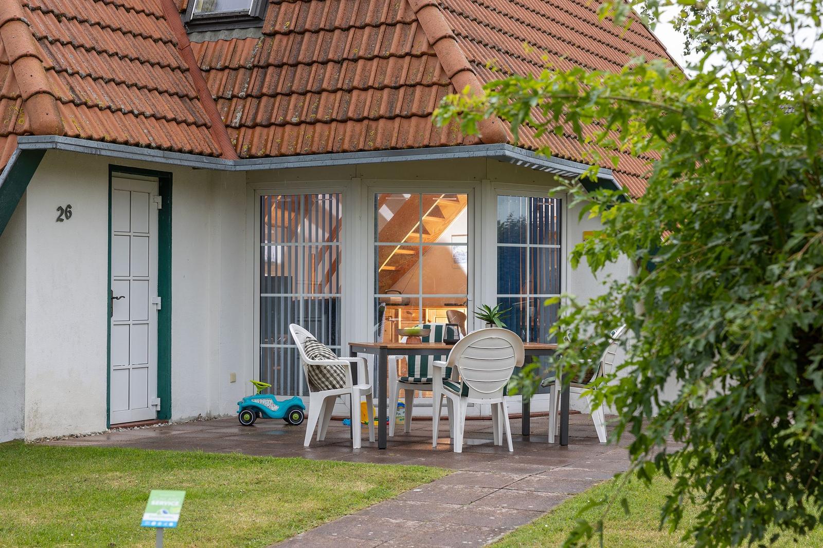 House with terrace, table, chairs, and toy. Interior passage visible.