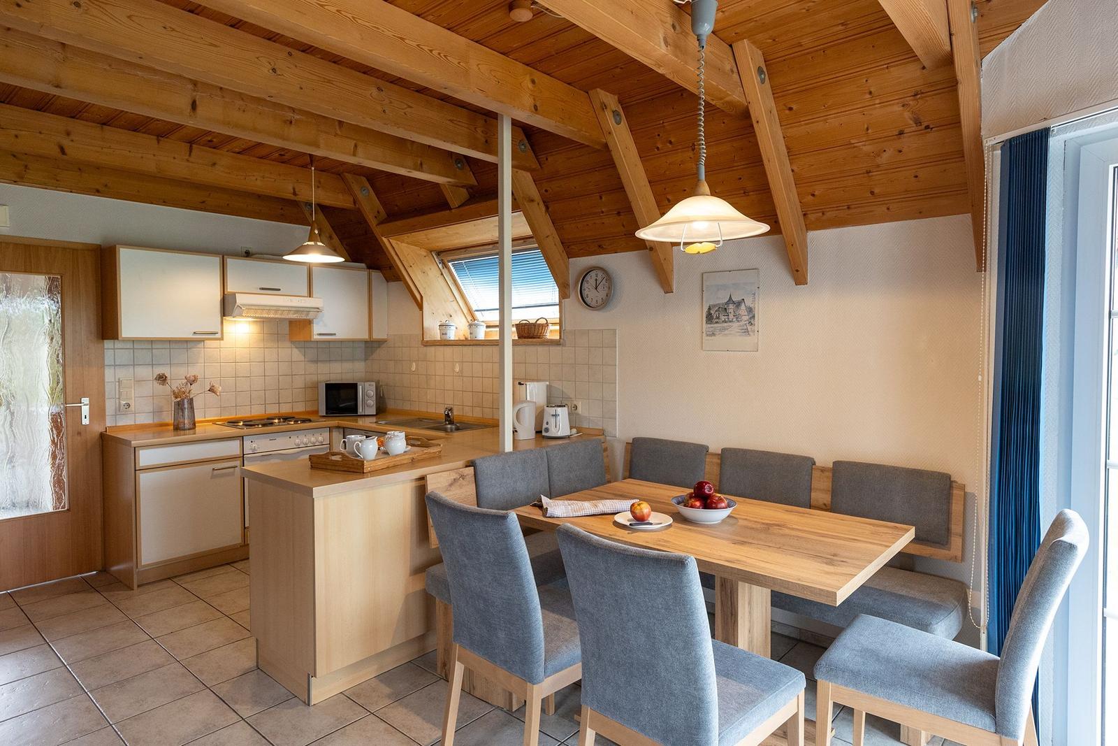 Kitchen with dining area under wooden ceiling with beams.