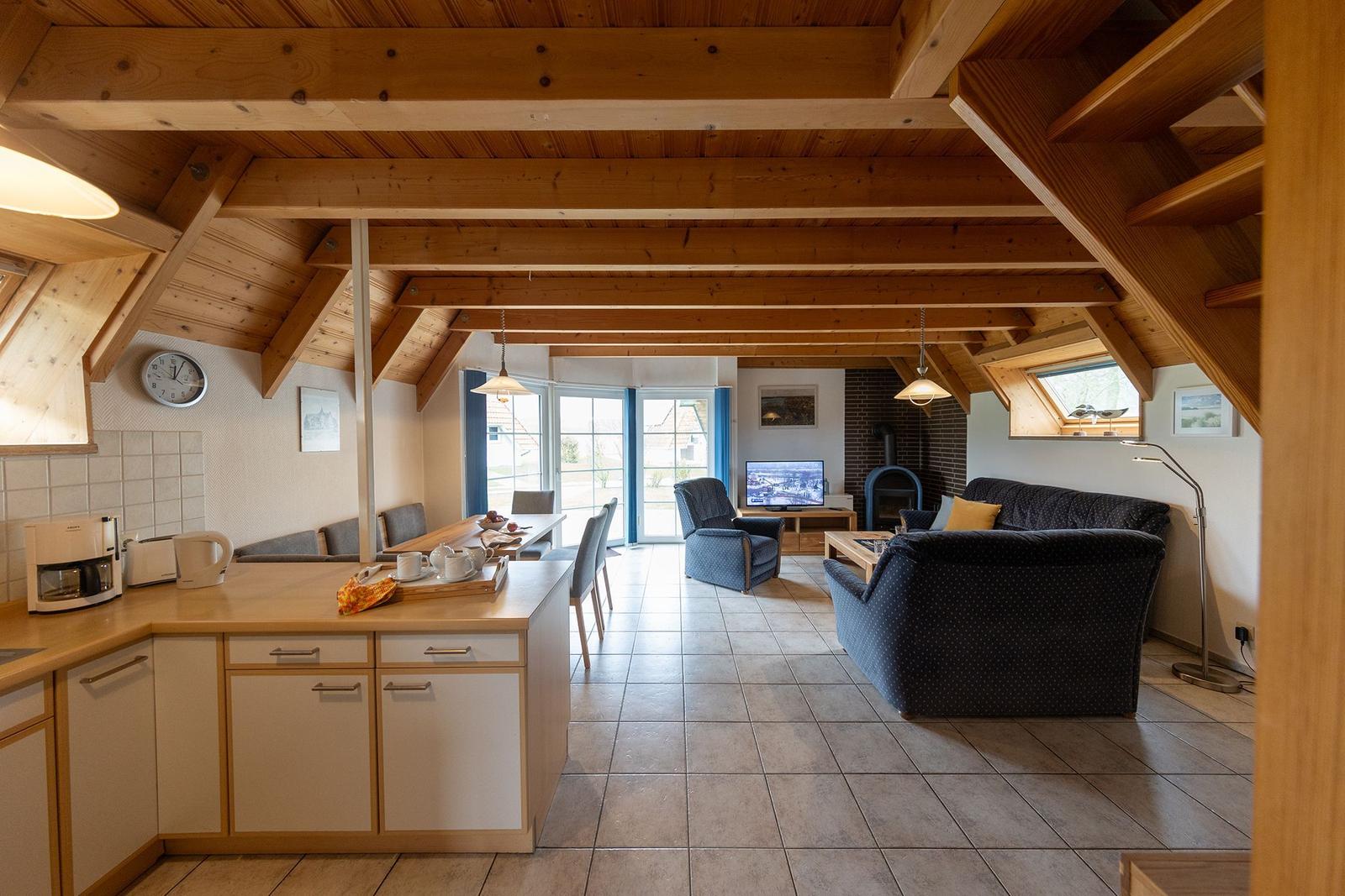 Kitchen and living room with wooden ceiling, sofa, TV, and kitchen counter.