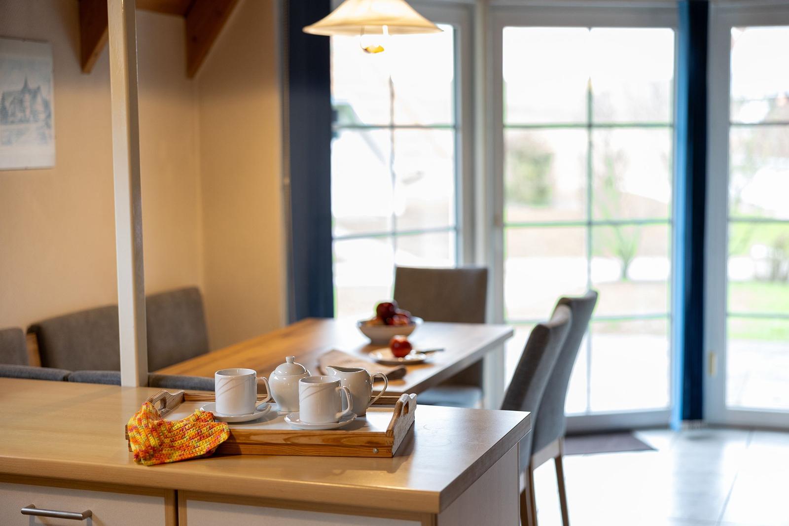 Dining area with table, chairs, and windows. A tea set is on the table.