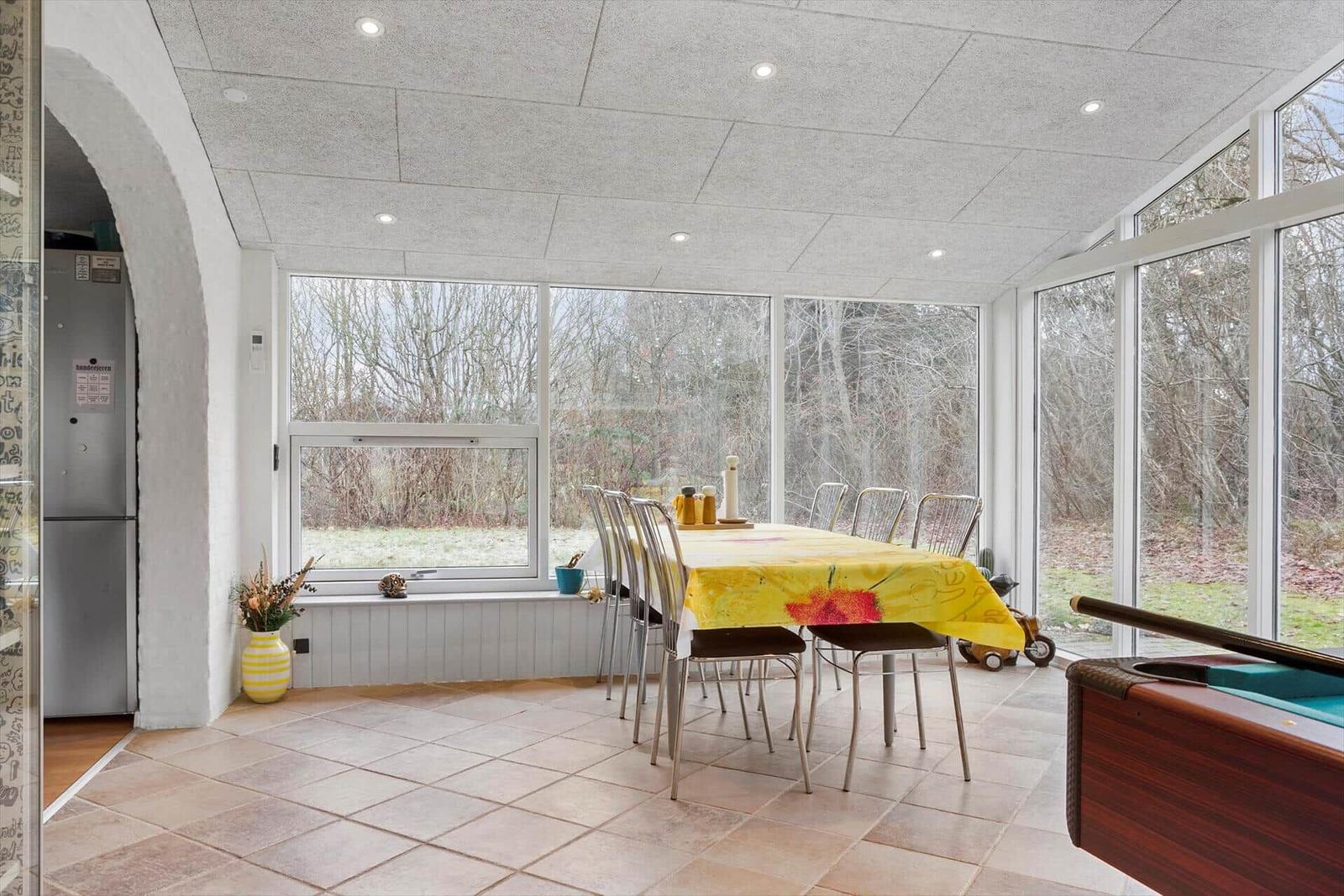 Esszimmer mit großem Fenster, Esstisch und Pooltisch. Blick auf Wald.