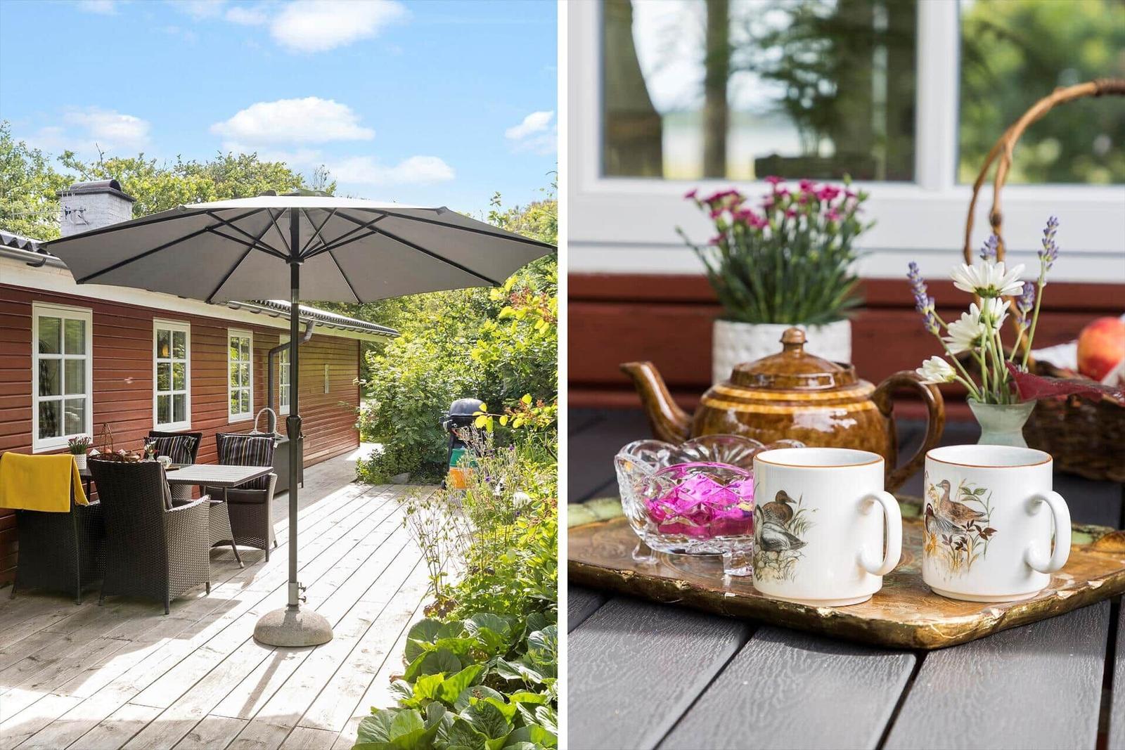 Terrasse mit Sonnenschutz und Garten. Tisch mit Tassen und Blumen auf Holztisch.