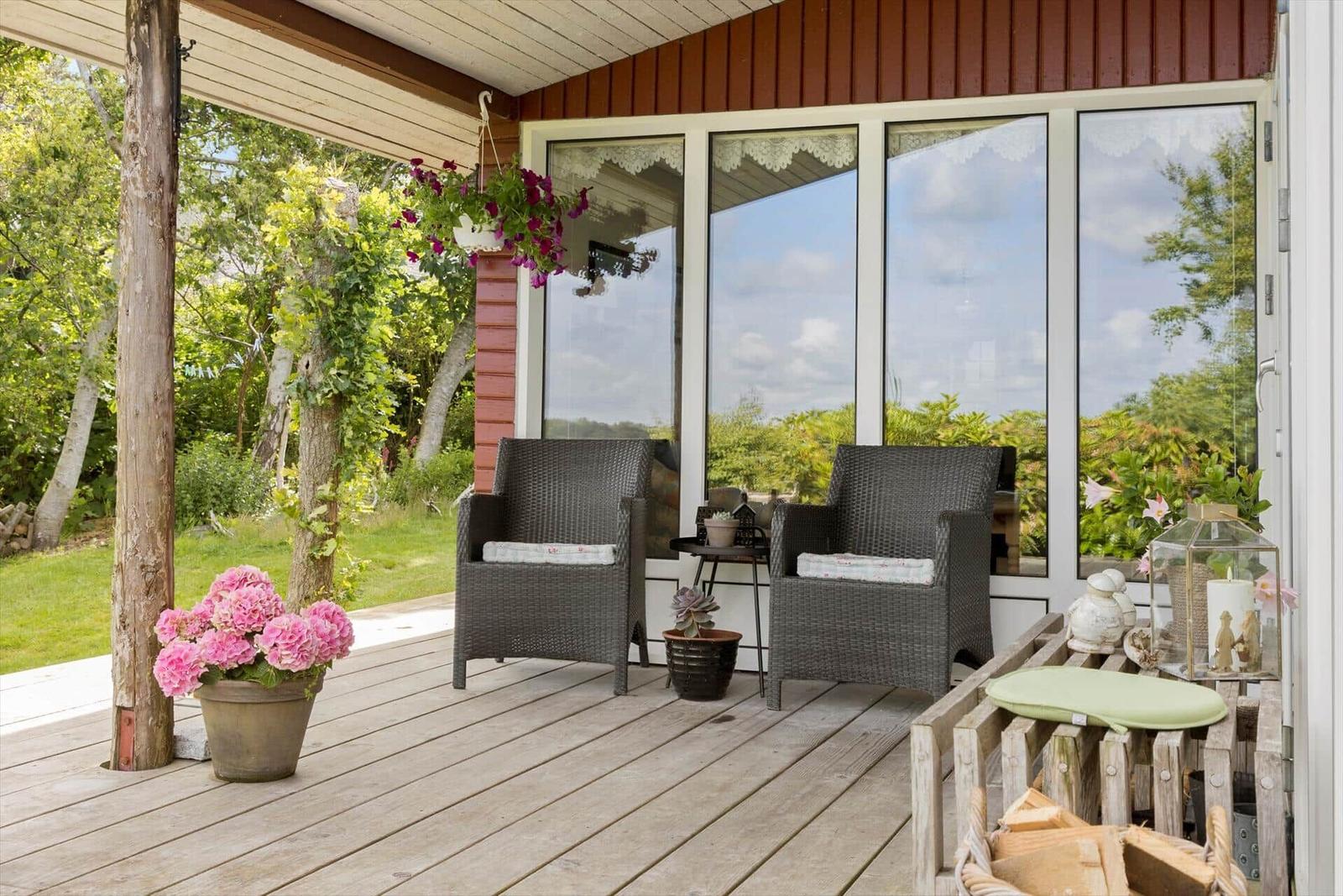 Terrasse mit zwei Sesseln, Blumen und Blick auf Garten.