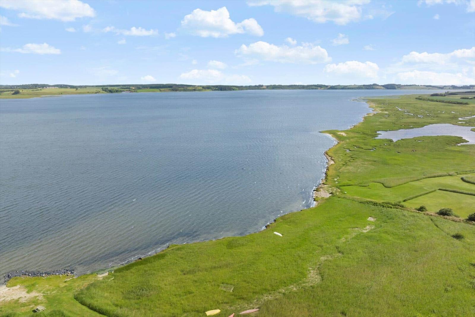 Großer See mit grüner Uferzone und klarem Himmel.