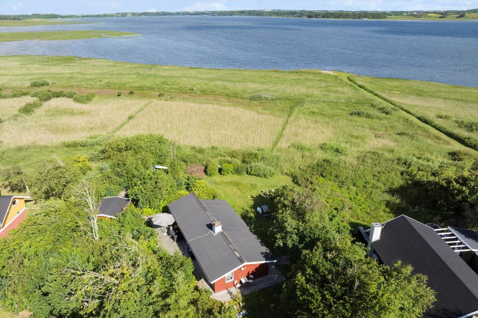 Roter Ferienhaus mit Terrasse und Blick auf einen See.