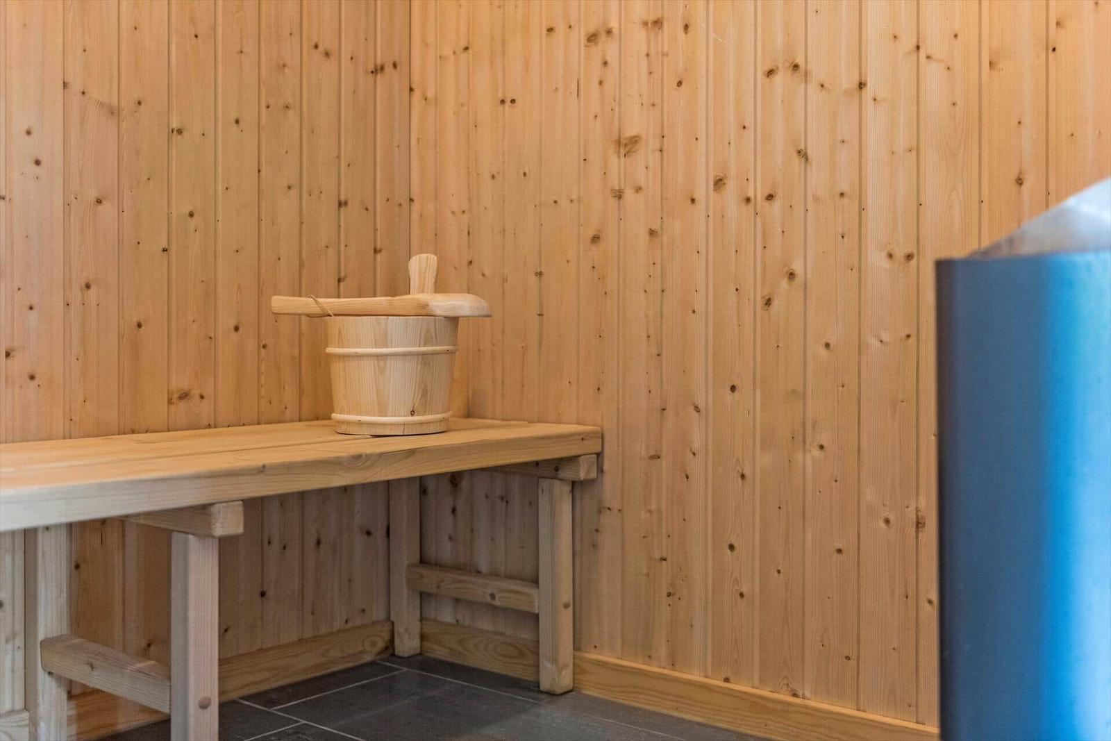 Holzsauna mit Bank und traditionellem Eimer.