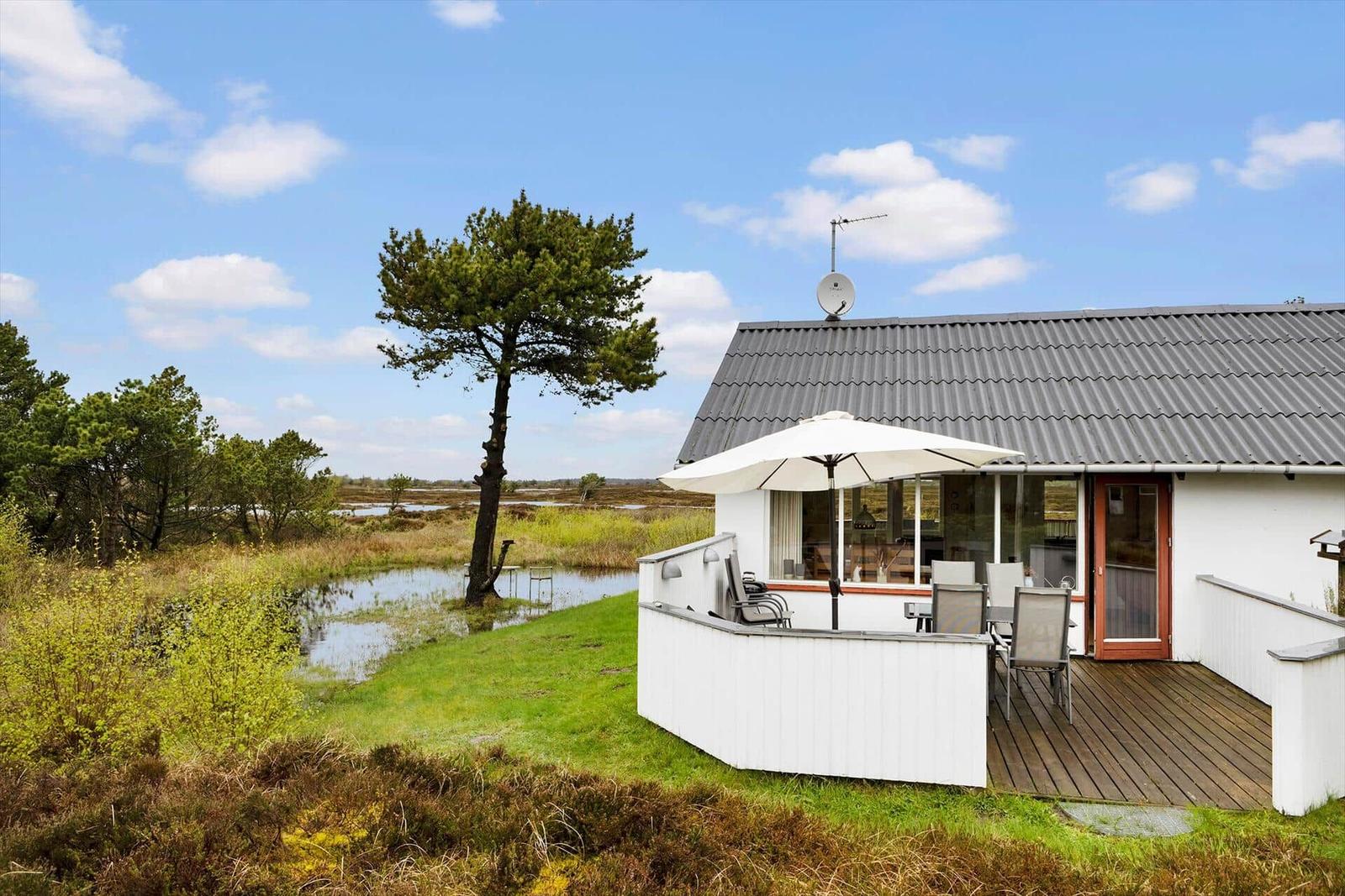 Wohnung mit Terrasse, Garten und Blick auf Moorlandschaft unter blauem Himmel.