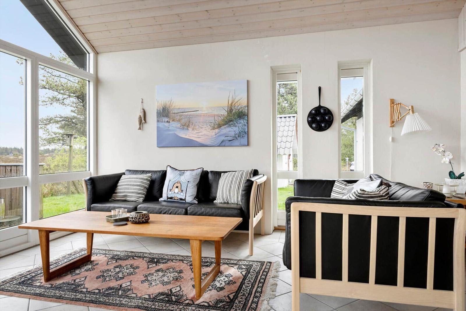 Ein Wohnzimmer mit zwei schwarzen Sofas, einem Holztisch und einem Teppich.