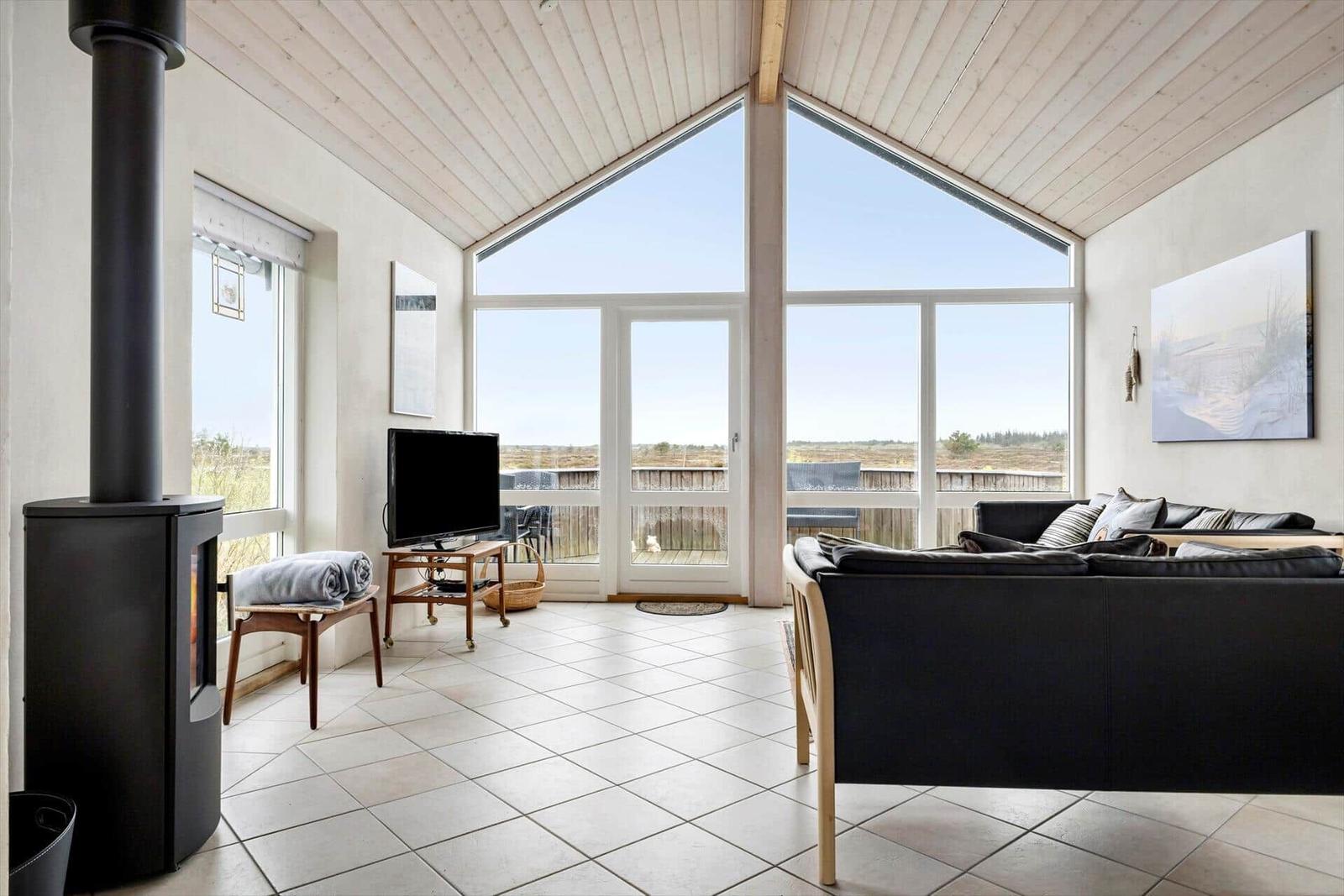 Wohnraum mit großem Fenster, Sofa, Kamin und TV.