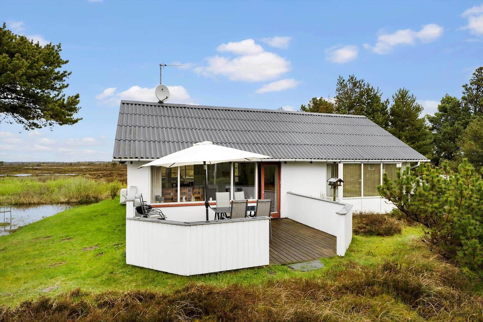 Wohnhaus mit Terrasse, Sonnenschutz und Garten. Blick aufs Wasser und Wald.