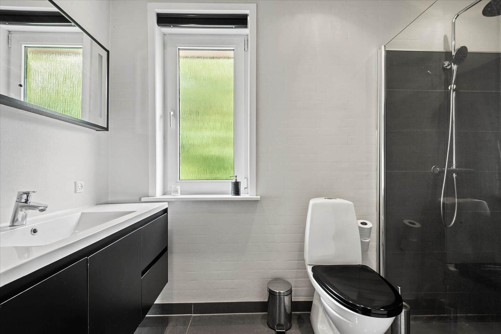 Badezimmer mit Dusche, Toilette und Waschbecken mit Spiegel