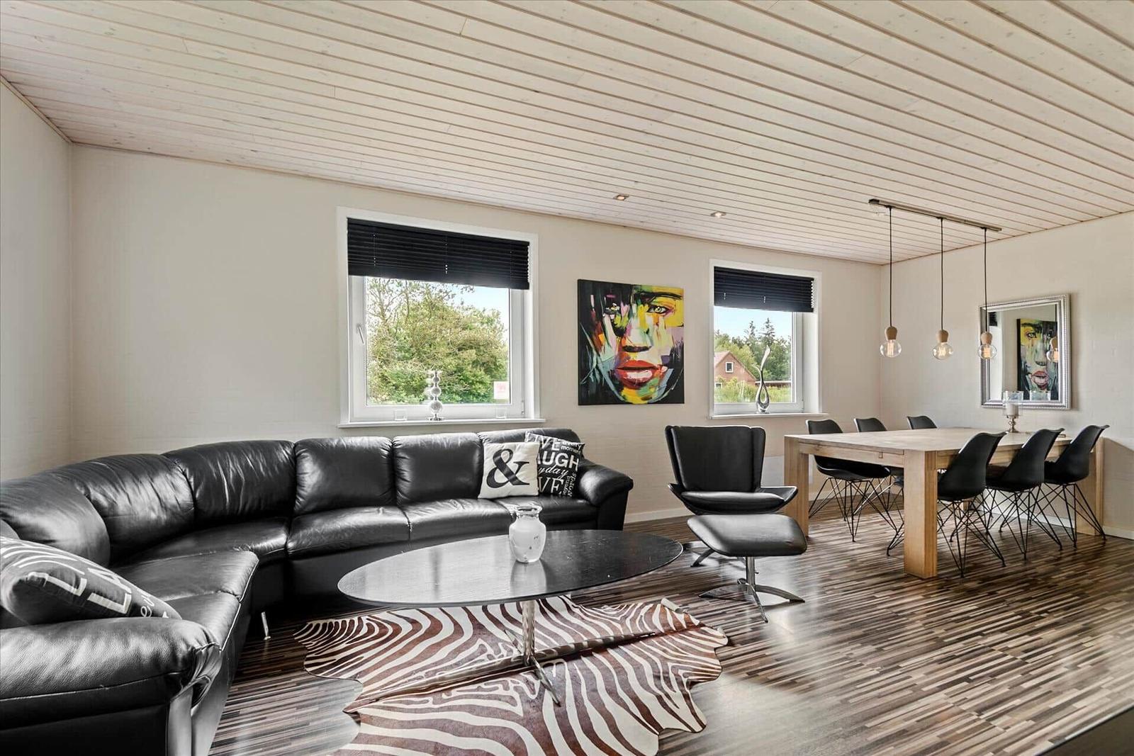 Wohn- und Essbereich mit Ledersofa, Holzboden und Wandbild.