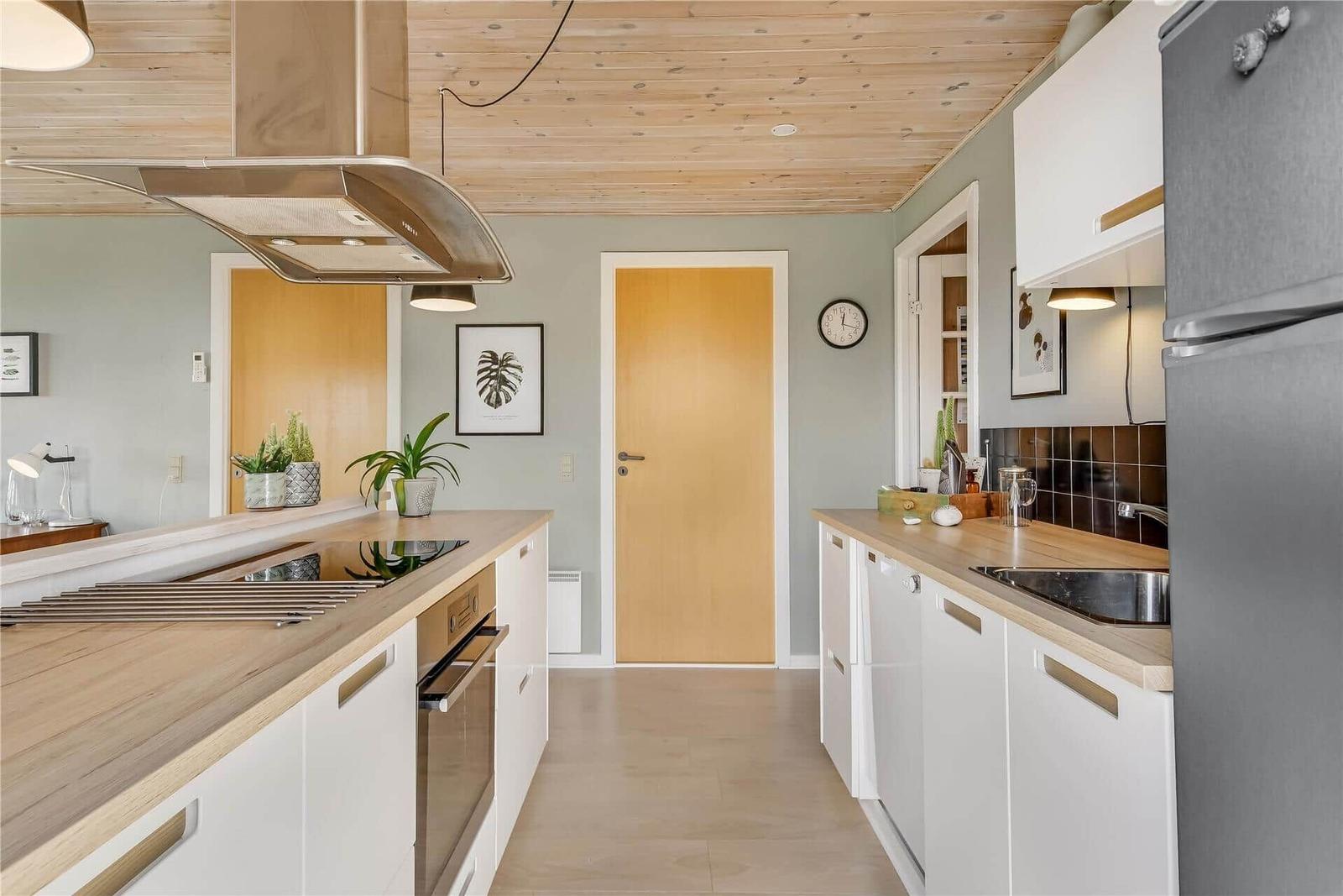 Moderne Küche mit Holzboden, weißen Schränken und Holzoberflächen.