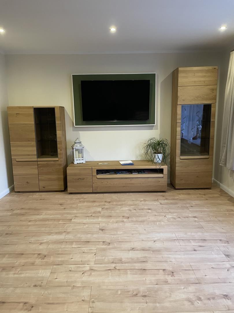 Wohnzimmer mit Holzmöbeln, Fernseher und Pflanze