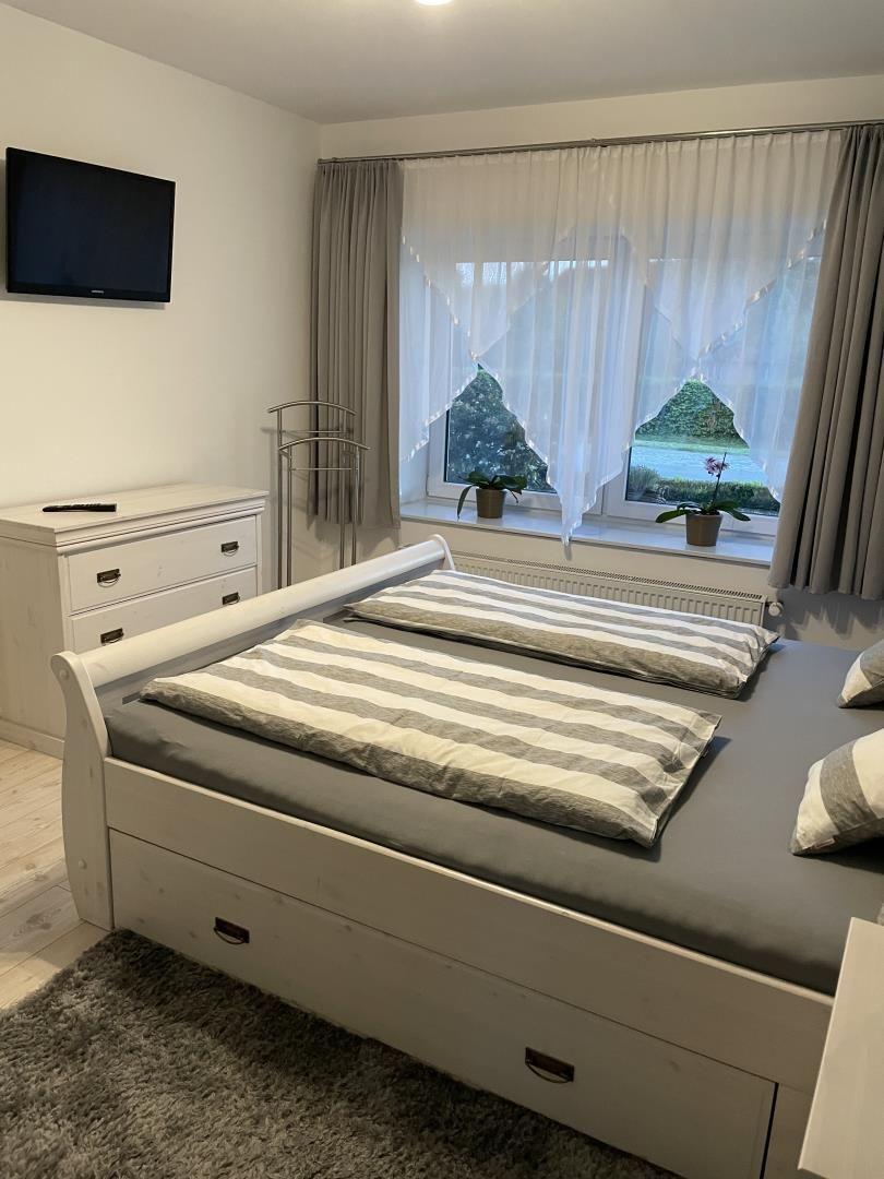 Schlafzimmer mit Doppelbett, TV und Fenster mit Blick auf den Garten.