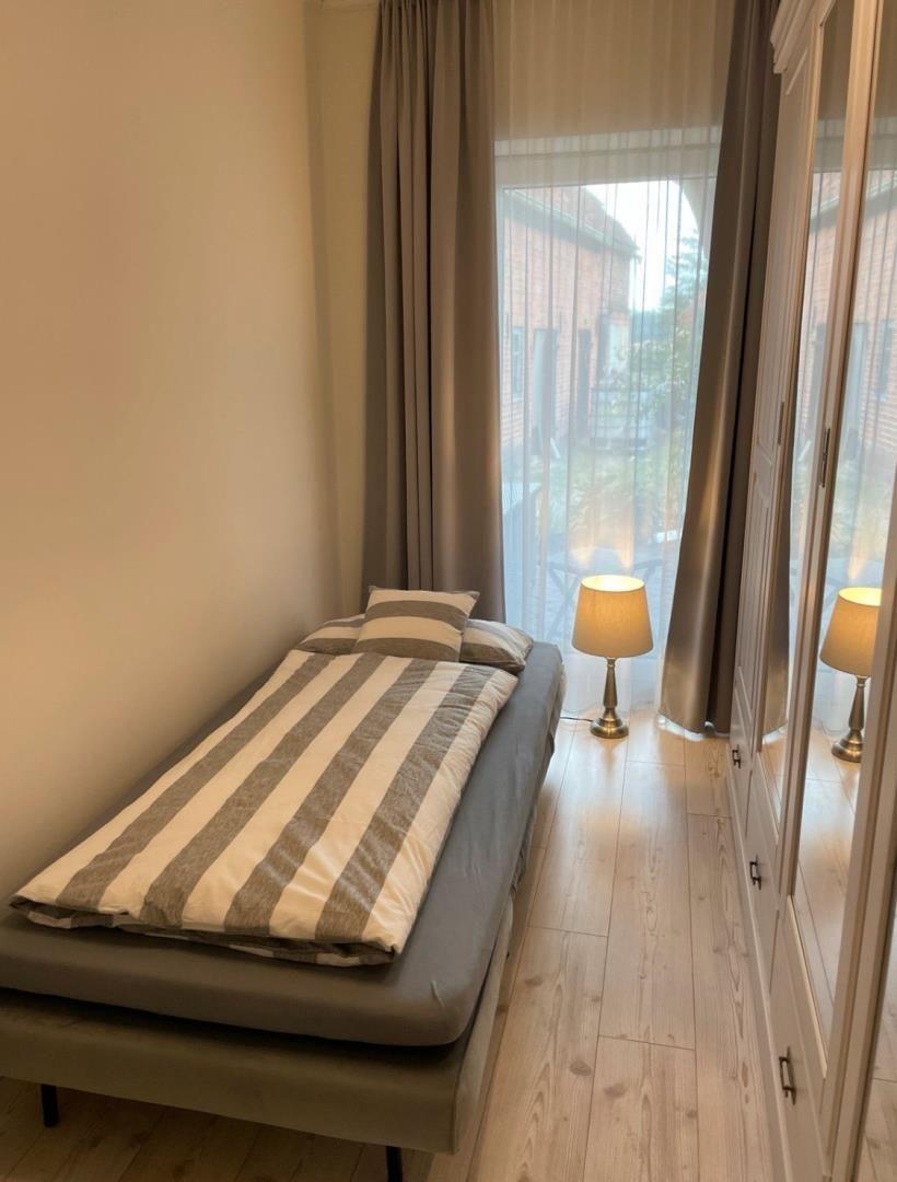 Ein Schlafzimmer mit einem Bett, einem Kleiderschrank und einem Fenster mit Vorhängen.