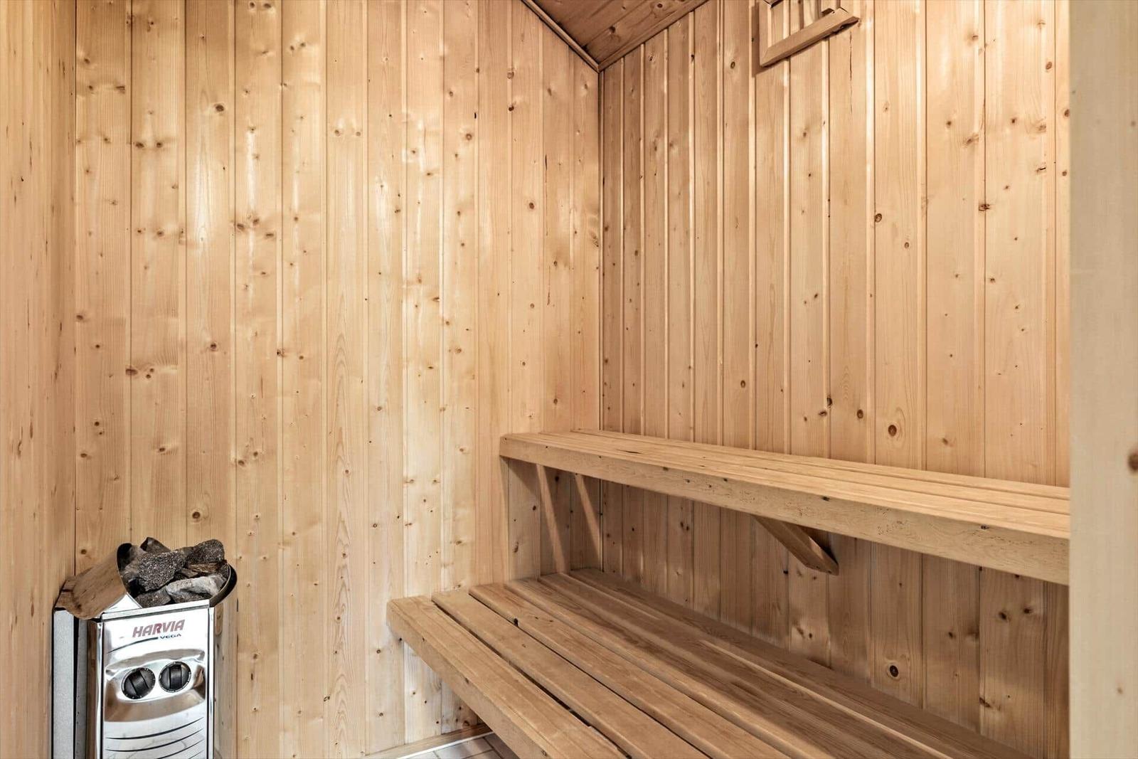 Sauna mit Holzwand und Sitzbänken. Heizung mit Steinen.
