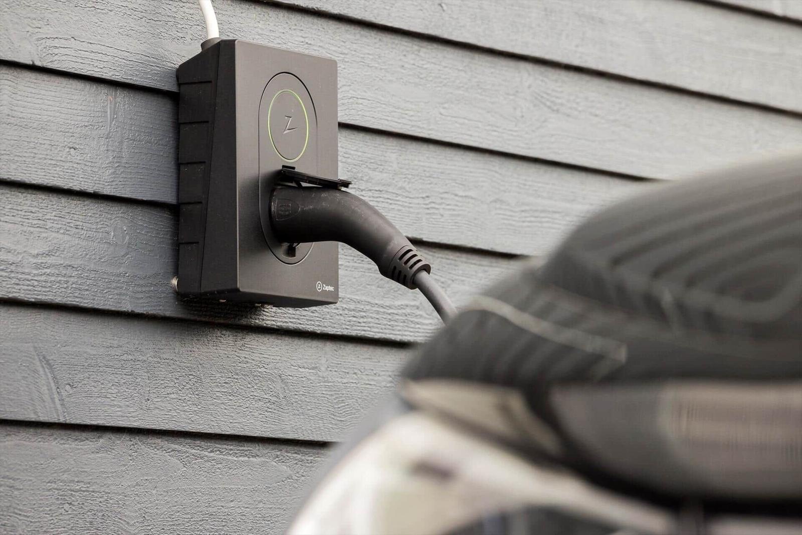 Elektrischer Ladeanschluss an Hauswand mit Stecker in Fahrzeug
