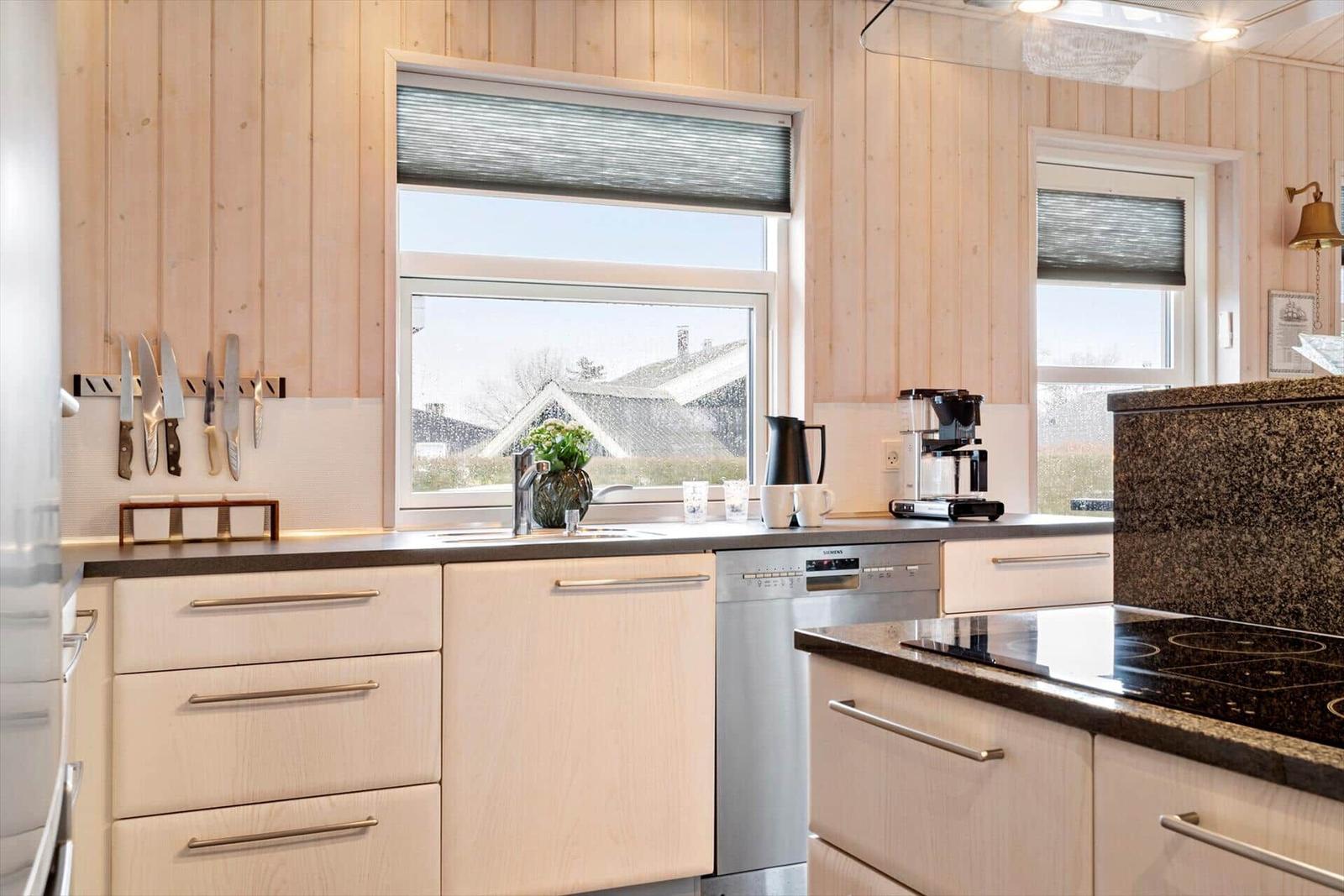 Küche mit Holzwänden, Arbeitsplatte und Fensterblick.