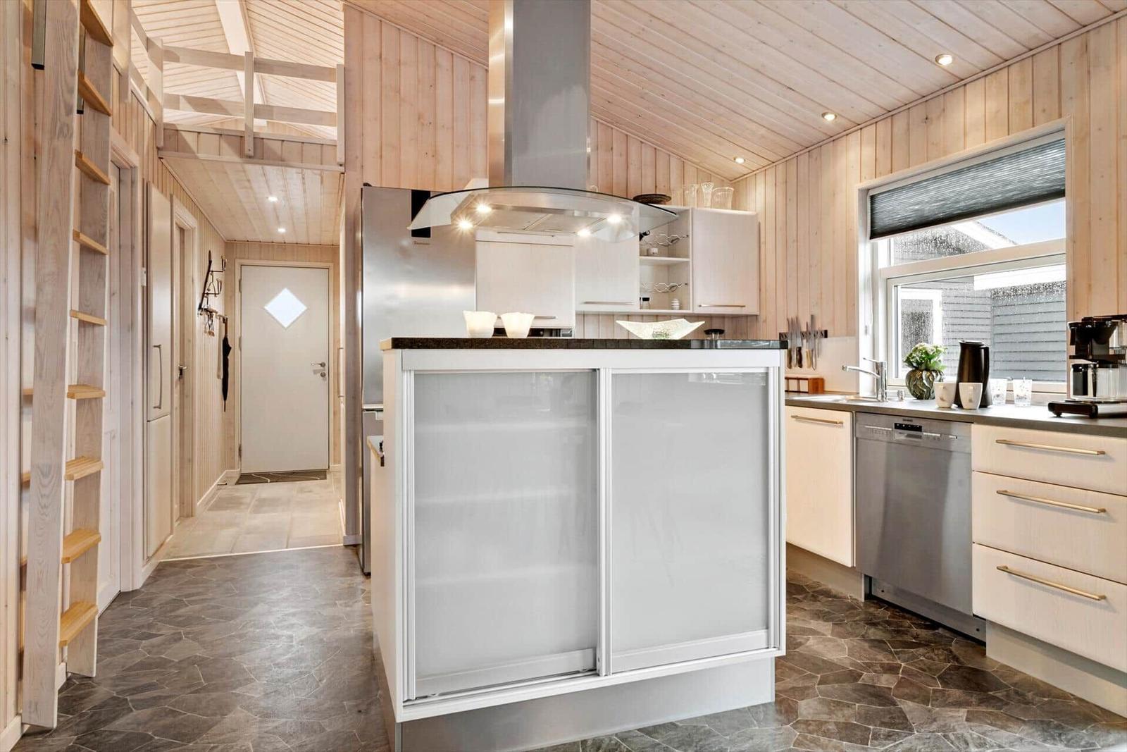Küche mit Holzwand, Edelstahlgeräten und zentraler Arbeitsinsel.