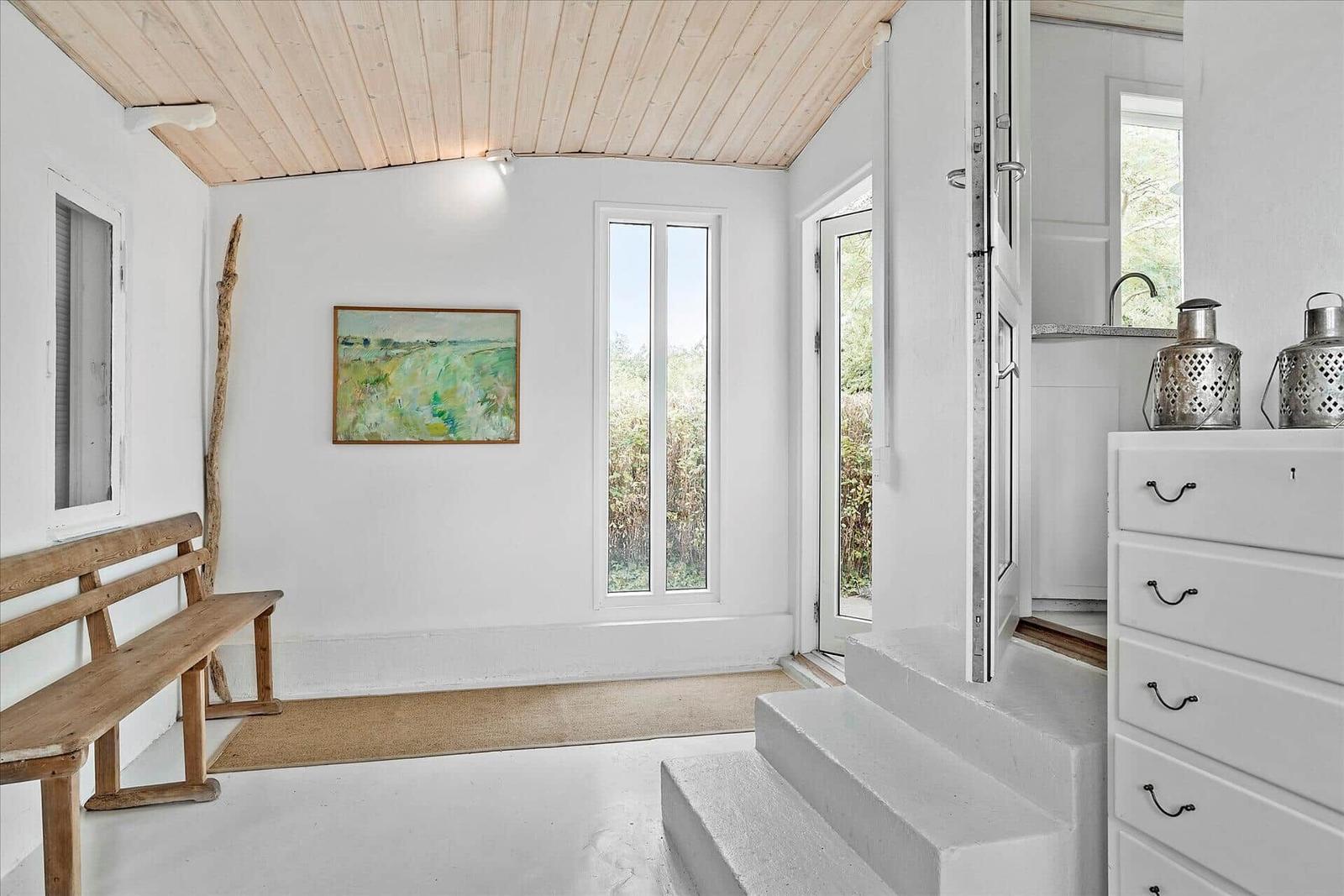 Eingangsbereich mit Holzbank, Wandbild und Treppe zur Küche.