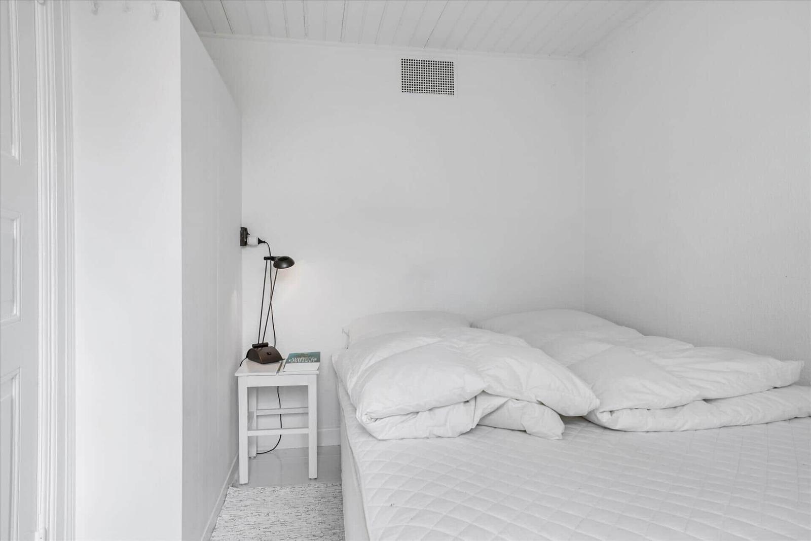 Ein Schlafzimmer mit weißer Bettwäsche, einem Nachttisch und einer Wandlampe.