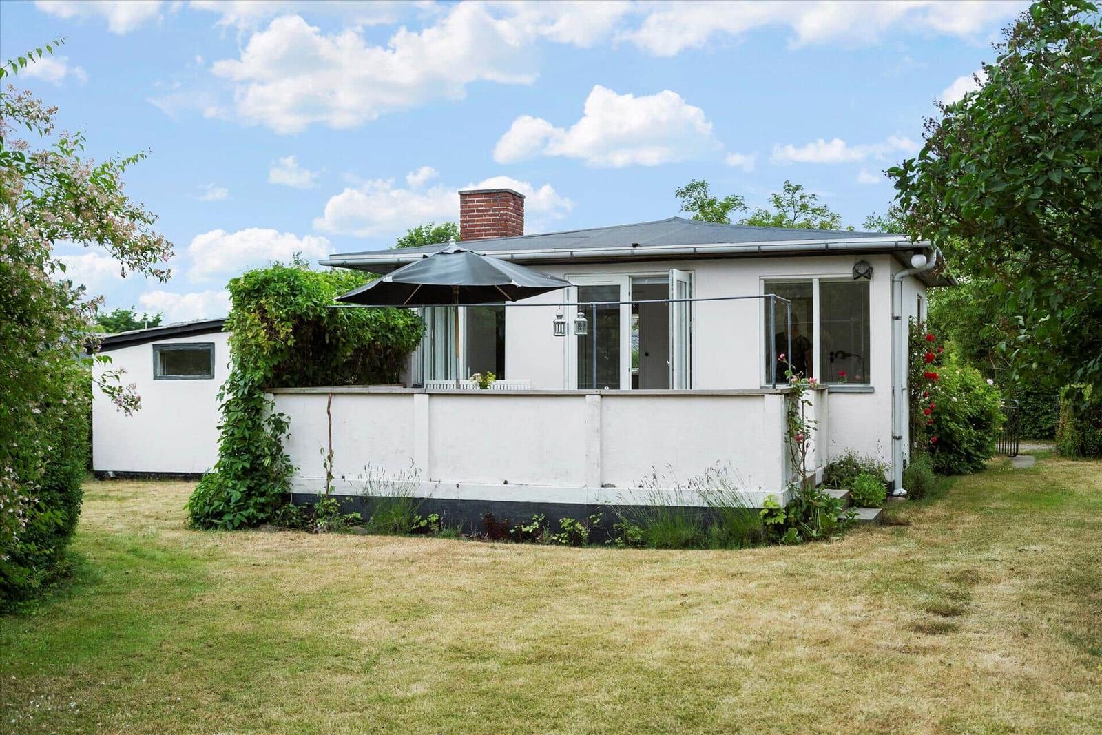 Weißes Haus mit Terrasse und Sonnenschirm im Garten