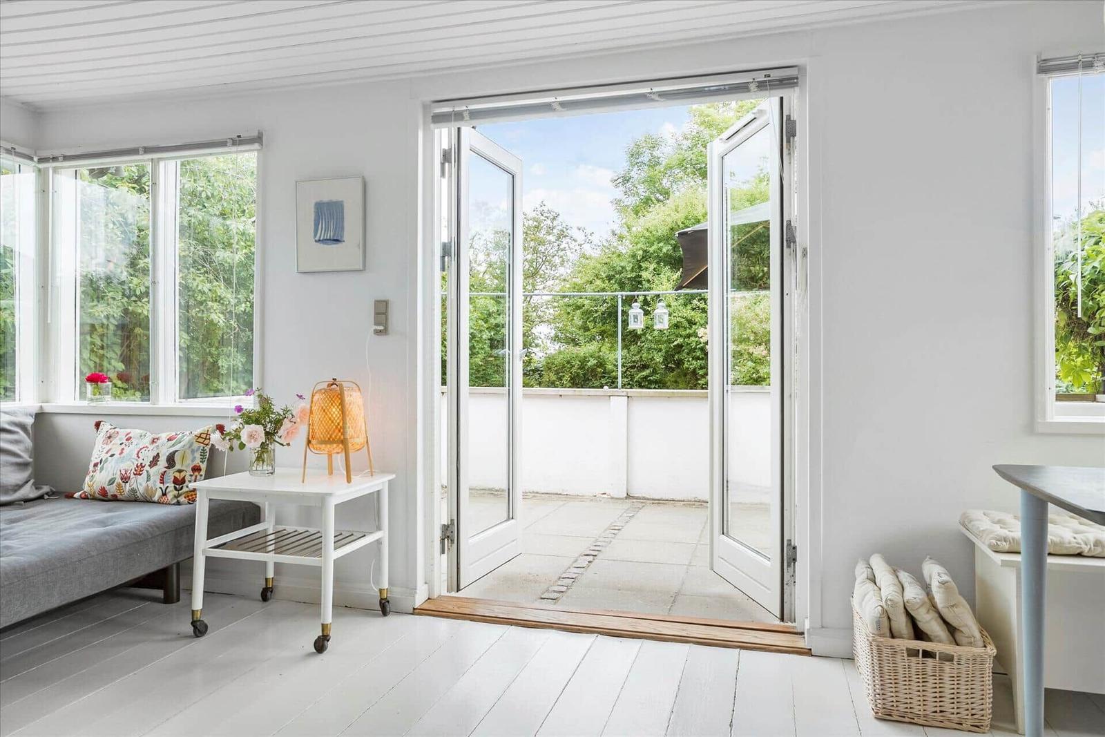 Wohnraum mit Blick auf Balkon, Fenster, Tisch und Stuhl.