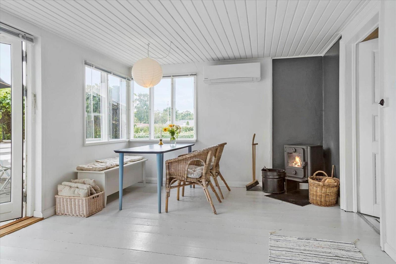 Essbereich mit Tisch, Stühlen und Kamin. Weiße Wände und Holzboden.