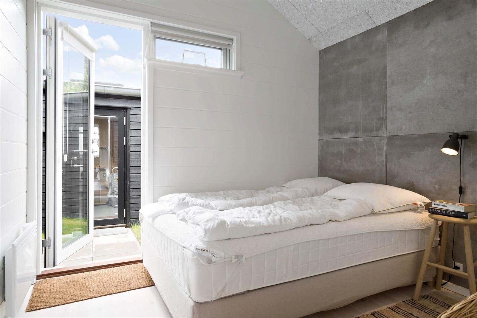 Schlafzimmer mit Bett, Fenster und Tür zum Außenbereich.