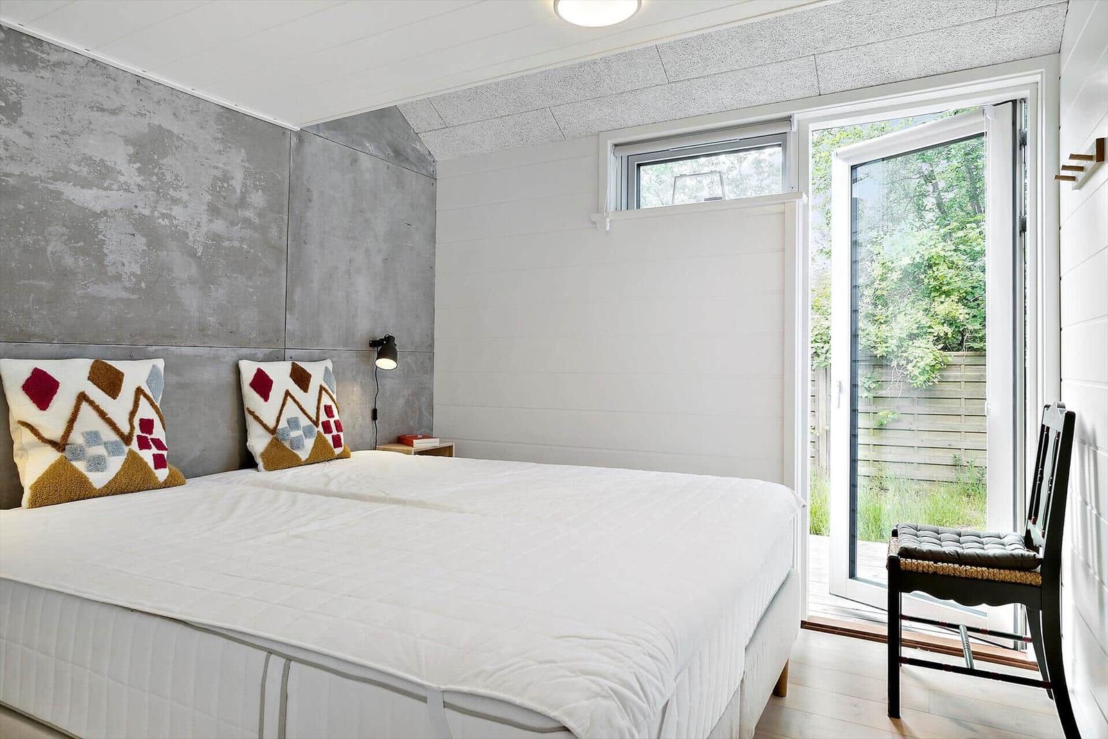 Schlafzimmer mit Bett, Kissen und Tür zum Garten.